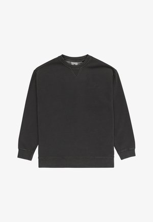Sudadera gris oscuro con cuello redondo y hombros caídos, combinada con pantalones holgados beiges. Zapatillas blancas y negras completan el conjunto.