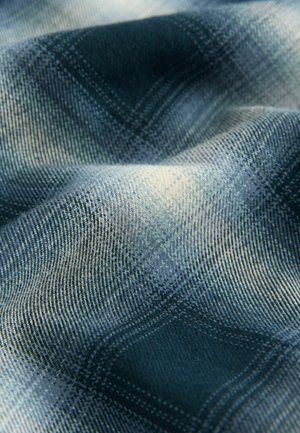 Tessuto a scacchi blu e grigio con una texture morbida, caratterizzato da un motivo intrecciato e gradienti sottili di colore sulla superficie.