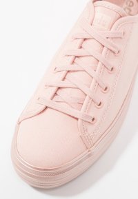 Baskets en toile rose clair avec lacets assortis et semelle en caoutchouc, dotées d'un bout arrondi et de détails cousus.