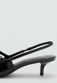 Svart patenterad läder slingback sandal med en låg, avsmalnande klack och minimalistisk design. Har smala remmar och en slät yta.