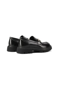 Scarpe di pelle nera con un design elegante, caratterizzate da una forma arrotondata, suola in gomma spessa e un accento dorato sulla parte superiore.