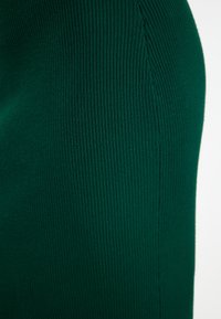 Groene ribfluweel stof, close-up weergave, met verticale textuur en naaddetails, gladde afwerking, gemiddelde dikte, eentonige kleur.
