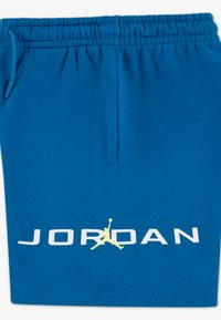 Μπλε αθλητικό σορτς από βαμβακερό μείγμα υφάσματος, με ελαστική μέση με κορδόνι, πλαϊνές τσέπες και μεγάλο λευκό λογότυπο "JORDAN" με κίτρινη σιλουέτα.