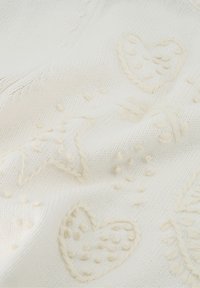 Gebreide stof in het wit met textuurpatronen in crèmekleur van harten en sterren. Zacht, met een subtiele, verheven oppervlakte en complexe stikdetails.