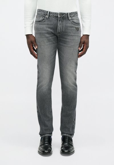 Γκρι τζιν παντελόνι με ίσια κοπή, διαθέτοντας πέντε τσέπες, ασημένια αξεσουάρ και λογότυπο στην πλάτη. Φοριέται με μαύρες αναπαυτικές παντόφλες.