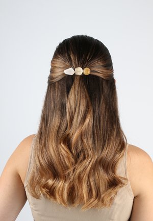 Haaraccessoire mit drei verschiedenen Edelsteinen in sanften Farbtönen, die an welligem braunem Haar befestigt sind und hinten gesichert werden. Glatte Textur und natürliche Formen.