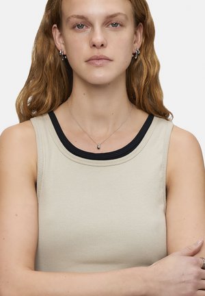 Beige gestreifter Tanktop mit schwarzem Kontrast-Ausschnitt, runder Kragen und ärmellosem Design. Eine schlichte silberne Halskette ist sichtbar.