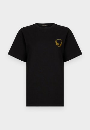 Melnā īsroku T-krekls ar mazām dzeltenām tīģera galvām, kas veido sirds formu uz kreisā krūšu daļas.