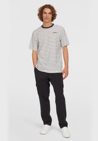 Stribet t-shirt i hvid og sort med crew neck, parret med sorte cargo bukser og hvide sneakers, med en afslappet pasform og løse ærmer.