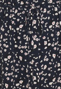 Námořnické šaty s květinovým vzorem, bílými a růžovými květinami, se skládacím pasem a vázáním vzadu. Vyrobeno z měkké tkaniny.