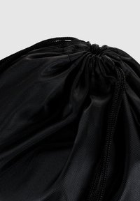Bolsa de cuerda negra hecha de tejido de nailon texturizado, que presenta una parte superior fruncida con un cordón duradero para el cierre y un acabado ligeramente brillante.