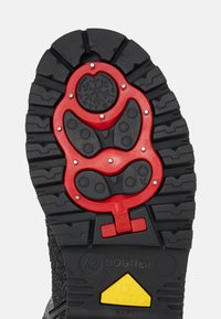 Černá podrážka gumové boty s výraznou červenou protiskluzovou vložkou se zvýrazněnými vzory, stříbrnými nýty a žlutým akcentem na patě s nápisem "SYSTEM ALPI".