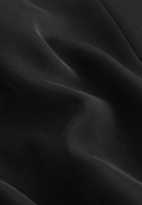 Tessuto nero a coste con una texture liscia, che presenta morbide pieghe e curve, con una leggera lucentezza sotto la luce, che evidenzia la sua qualità elastica.