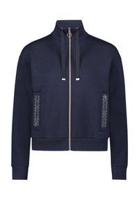 Navy blue zip-up jacket made from soft fabric, featuring a high collar, two front pockets with studded accents, and ribbed cuffs.