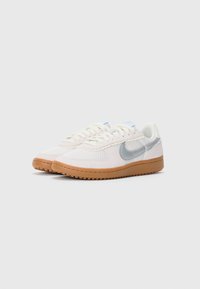Biele sieťované tenisky s svetlomodrými akcentmi a reflexným strieborným logom Nike. Textúrovaná gumená podrážka. Šnurovací dizajn.