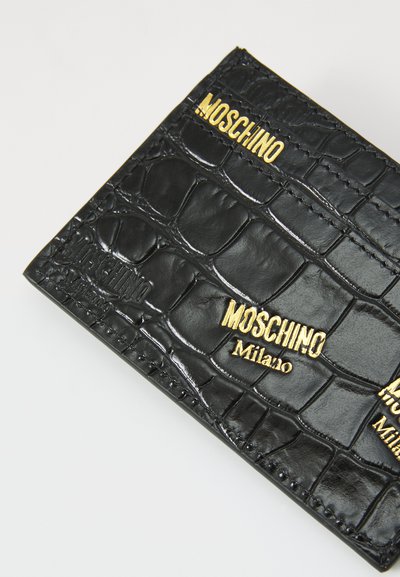 Črn falski krokodilni denarnica s podrobnostmi logotipa, vgraviranimi v zlati barvi. Teksturna površina z elegantnim dizajnom in kontrastnim šivanjem.