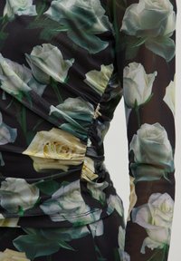 Langarm-Oberteil aus transparenter Stoff mit einem schwarzen Hintergrund und einem floralen Muster aus weißen und grünen Rosen, gerafften Details an der Seite.