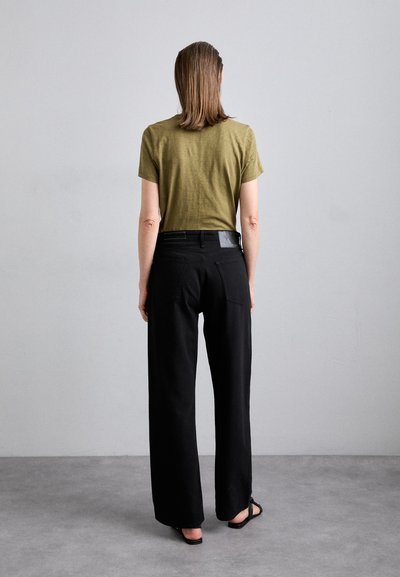 Olive green short-sleeve shirt paired with black wide-leg trousers. The trousers feature a sleek waistband with a textured detail at the back.