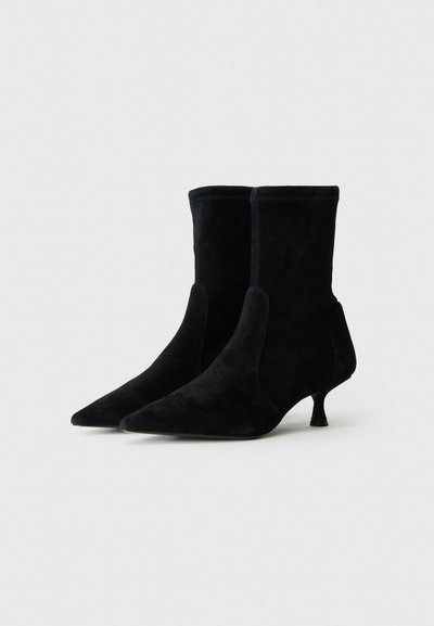 Svarta mocka ankelskor med spetsig tå, smal kittenklack och elastiska sidopaneler. Slät textur och minimalistisk design.