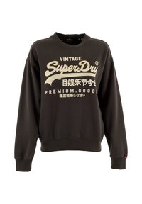 Zwarte trui met een ronde halslijn, geribbelde zoom en manchetten, met een groot wit "SuperDry"-logo en tekst gedrukt op de voorkant.