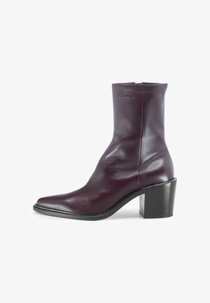 Stivale alla caviglia in pelle borgogna con punta appuntita, texture liscia e un robusto tacco a blocco. Chiusura con zip sul retro per una facile calzata.