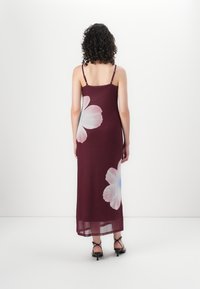 Vestido maxi cor bordô com alças finas, apresentando grandes estampas florais brancas. Tecido leve com textura suave, design até o tornozelo.