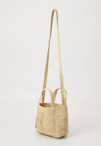 Vevd stråveske i lys beige, med teksturert overflate, to korte håndtak og en lang justerbar stropp. Blomsterdetalj.