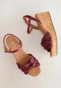Sandales compensées à brides bordeaux tressées, boucle à la cheville, semelle intérieure beige et semelle plateforme texturée liège, vues de dessus sur fond clair.