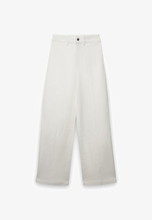 Pantalon blanc à jambes larges en tissu coton, avec une taille haute, de grands plis avant et un seul bouton noir à la taille.