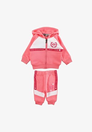 Survêtement deux pièces rose en tissu doux. Comprend un sweat à capuche zippé avec des accents blancs et un logo, associé à un pantalon à taille élastique.
