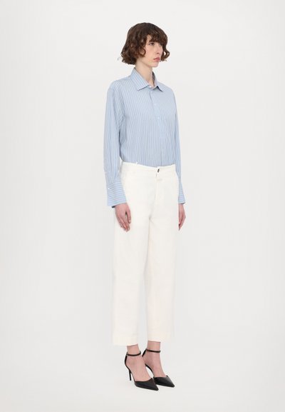 Light blue striped shirt with long sleeves, paired with high-waisted white trousers and black pointed-toe heels. Minimalist design.