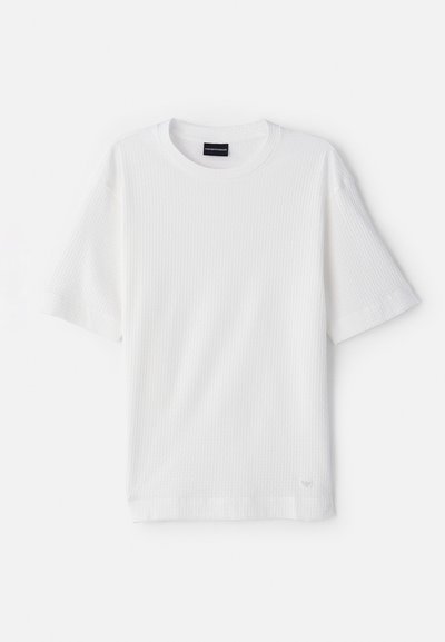 Tricou alb cu mânecă scurtă, fabricat dintr-un material texturat, cu striții. Prezintă un guler rotund și un mic logo accentuat aproape de tiv.