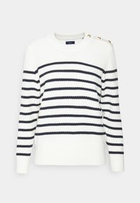 Valkoinen neule, jossa laivastonsiniset vaakaraidat, resorikuvio, pyöreä pääntie ja kultaiset nappikoristeet olkapäällä.