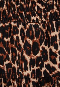 Leopardprint stof met een gestructureerd oppervlak in tinten zwart, bruin en crème, gerangschikt in een patroon over het materiaal.
