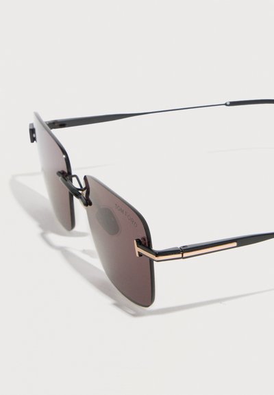 Rimless rectangular Tom Ford sunglasses with dark tinted lenses and thin black arms featuring gold accent near hinges.