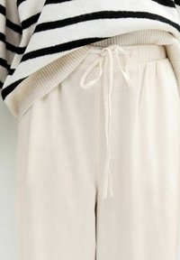 Losse crème broek met een elastische tailleband en trekkoord. Draag je met een zwart-witte gestreepte oversized trui, met ribgebreide randen.