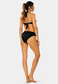 Czarny bikini z dekoltem halter i zawiązanym tyłem, charakteryzujące się prostym, gładkim wzorem oraz spodenkami zapewniającymi umiarkowane przykrycie, idealne do noszenia na plaży.