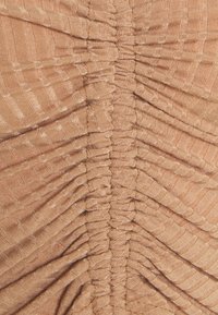 Texturerad tyg i varm persika, med vertikala veck och ribbade mönster, vilket skapar en dynamisk visuell effekt. Slät finish.