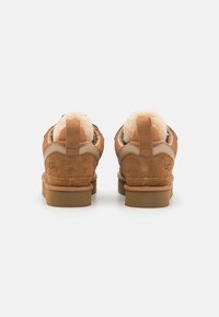 Bruine suède schoenen met een zachte, beige bontvoering en rubberen zolen. Voorzien van een platte hak en gestikte details langs de zijkanten.