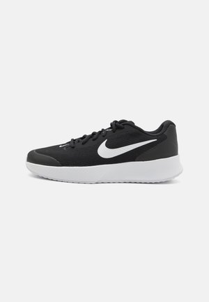 Chaussure de running Nike noire et blanche avec tige en mesh, logo swoosh blanc, laçage à l’avant et semelle blanche épaisse sur fond uni.