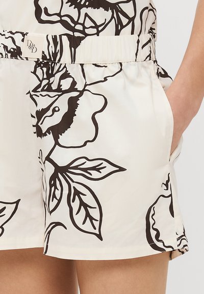 Calças curtas florais em tecido creme com grandes padrões de flores e folhas pretas. Cintura elástica com bolsos laterais e um corte descontraído.