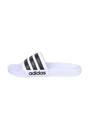 Sandalia tipo slide blanca de Adidas con tres rayas negras en la tira y logo negro de Adidas en el lateral, suela plana con amortiguación Cloudfoam.