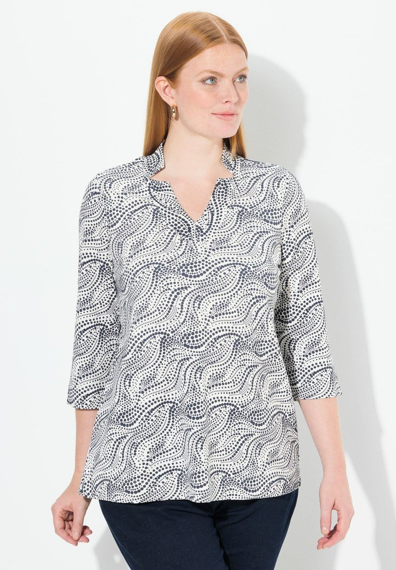 Weiße Bluse mit Navy-Wellen- und Punktmuster, mit Kragen und drei Viertelärmeln, aus leichtem Stoff gefertigt.