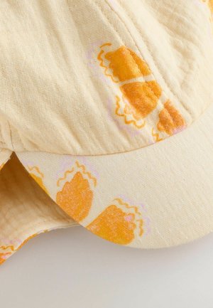 Chapeau jaune clair en tissu texturé, avec des motifs abstraits orange et rose, doté d'un bord courbé et de détails de couture.