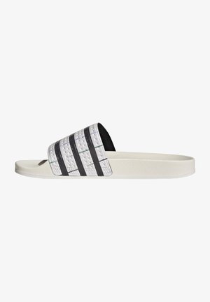 Hvide slidesandal med teksturerede sorte striber på remmen og flad sål, vist fra højre side.