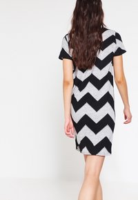 Abito a pois zigzag in bianco e nero, con maniche corte, lunghezza al ginocchio, in tessuto morbido, caratterizzato da un design a zigzag e scollatura rotonda.