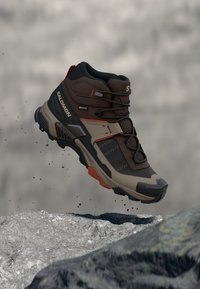 Μποτάκι πεζοπορίας μέσου ύψους με καφέ, γκρι και μαύρο χρωματικό συνδυασμό. Κατασκευασμένο από υλικά με υφή συνθετικού τύπου, με ανθεκτική σόλα και σύστημα κορδονιών.
