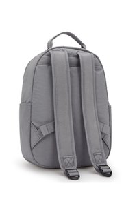 Sac à dos gris en tissu durable, de forme structurée, avec des bretelles réglables et une poignée supérieure. Comprend des poches latérales et des coutures renforcées.