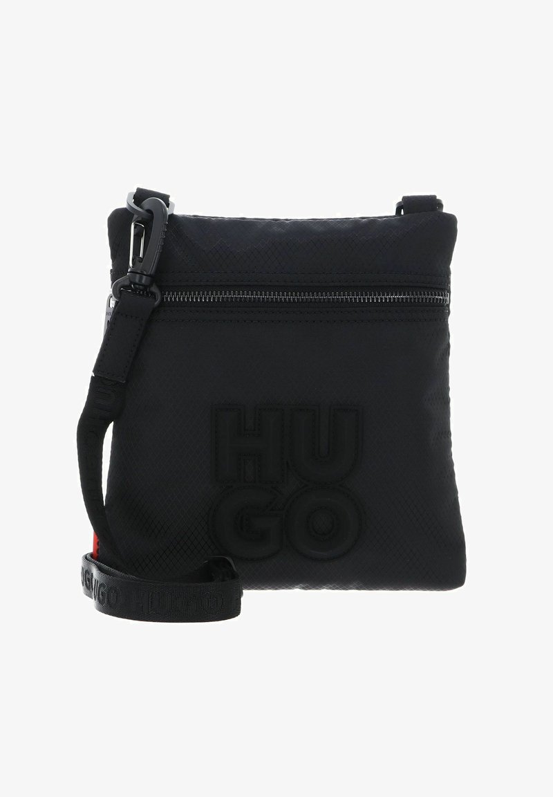 Sac bandoulière noir en tissu texturé, avec une fermeture éclair sur le dessus, un logo embossé et une sangle ajustable. Détails en rouge.