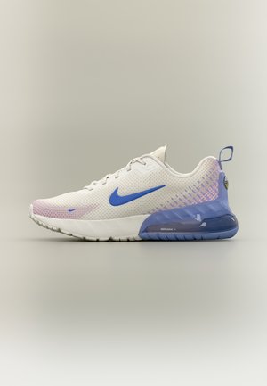 Baltas un violetas Nike Air Max sporta apavu pāris ar zilu Swoosh logotipu un redzamu gaisa spilvena zoli pret neitrālu fonu.